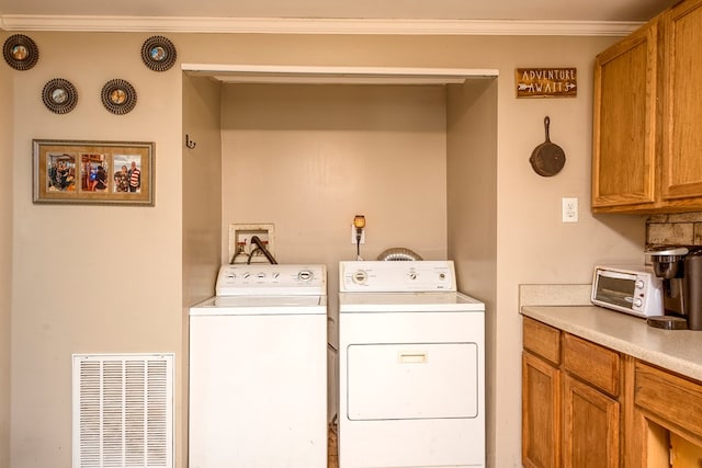 laundry area featuring washing machine and dryer, visible vents, a toaster, and ornamental molding