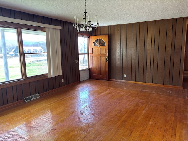 4127 Steelsburg Hwy, Cedar Bluff, VA 24609 - unfurnished room with a chandelier, hardwood / wood-style floors, a textured ceiling, wooden walls, and baseboards