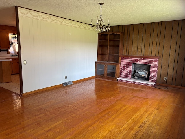 4127 Steelsburg Hwy, Cedar Bluff, VA 24609 - unfurnished living room with hardwood / wood-style floors, a chandelier, baseboards, a textured ceiling, and wooden walls
