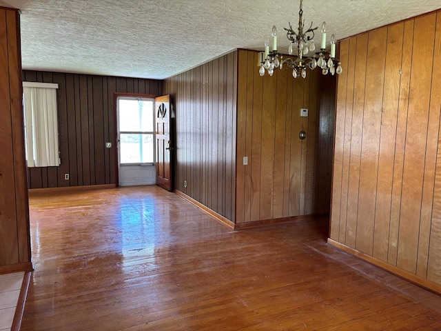 4127 Steelsburg Hwy, Cedar Bluff, VA 24609 - unfurnished dining area with a chandelier, hardwood / wood-style flooring, a textured ceiling, wood walls, and baseboards
