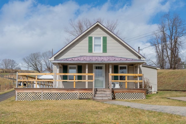rear view of property with a lawn, covered porch, and metal roof