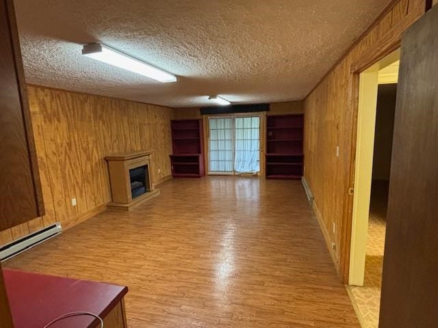 319 Bogey Dr, Abingdon, VA 24211 - unfurnished living room with light wood-type flooring, wood walls, a glass covered fireplace, and a textured ceiling
