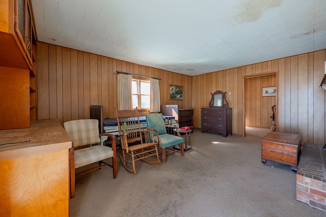 sitting room with light carpet and wood walls