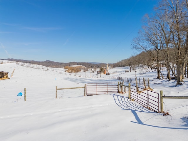 yard layered in snow featuring a rural view and a mountain view