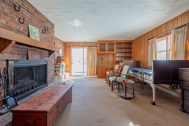 carpeted living room featuring a brick fireplace and wooden walls