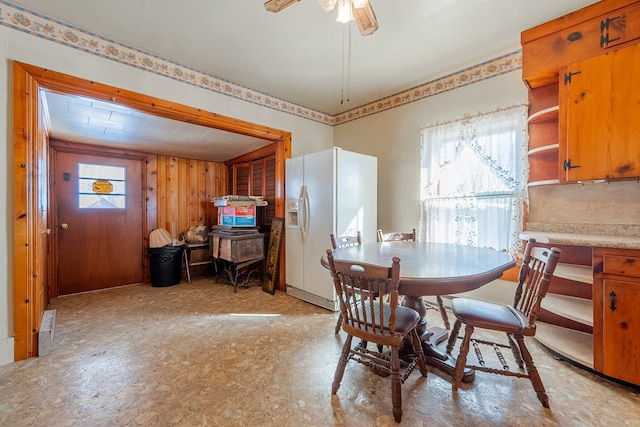 dining area featuring ceiling fan and wood walls