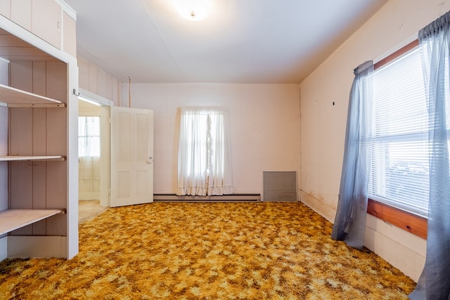 carpeted empty room featuring a baseboard heating unit and a wealth of natural light