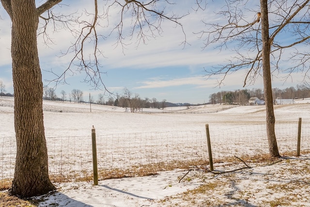 yard covered in snow featuring a rural view