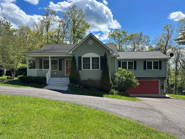 single story home featuring asphalt driveway, a garage, covered porch, a front lawn, and roof with shingles