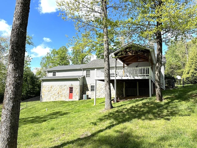 back of house featuring stone siding, a wooden deck, a yard, and central air condition unit