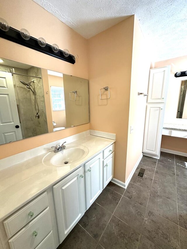 full bathroom with a textured ceiling, tile patterned floors, a shower, vanity, and baseboards