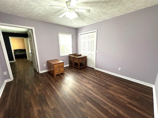 bedroom with baseboards, dark wood-type flooring, a textured ceiling, a closet, and a ceiling fan