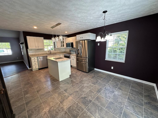 kitchen with stainless steel appliances, a chandelier, a sink, baseboards, and glass insert cabinets