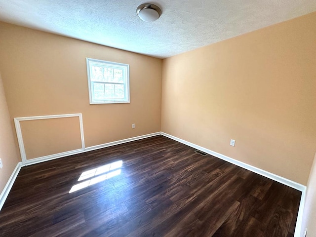 unfurnished room with dark wood finished floors, baseboards, and a textured ceiling