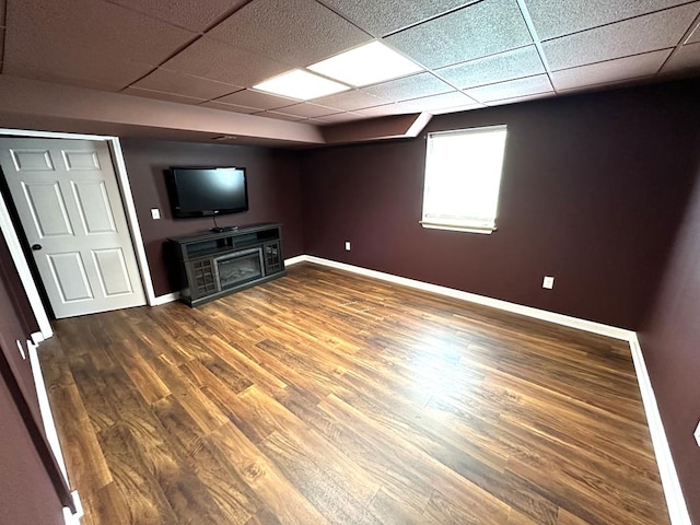 unfurnished living room featuring baseboards, a paneled ceiling, wood finished floors, and a fireplace
