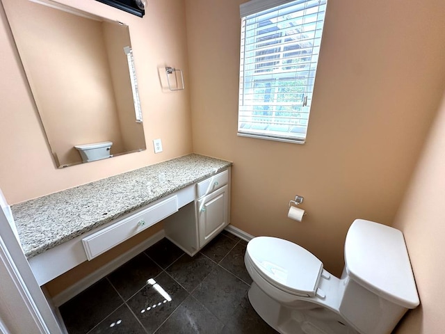 bathroom with toilet, healthy amount of natural light, tile patterned floors, and vanity