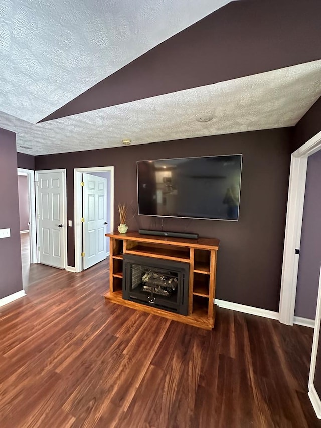 unfurnished living room with a textured ceiling, baseboards, and wood finished floors
