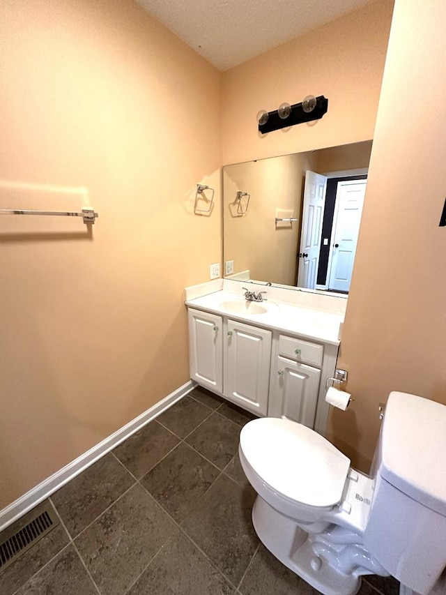 bathroom with toilet, vanity, tile patterned floors, and baseboards
