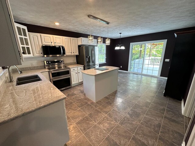 185 Laurel Dr, Fancy Gap, VA 24328 - kitchen with appliances with stainless steel finishes, a sink, a center island, white cabinets, and a textured ceiling