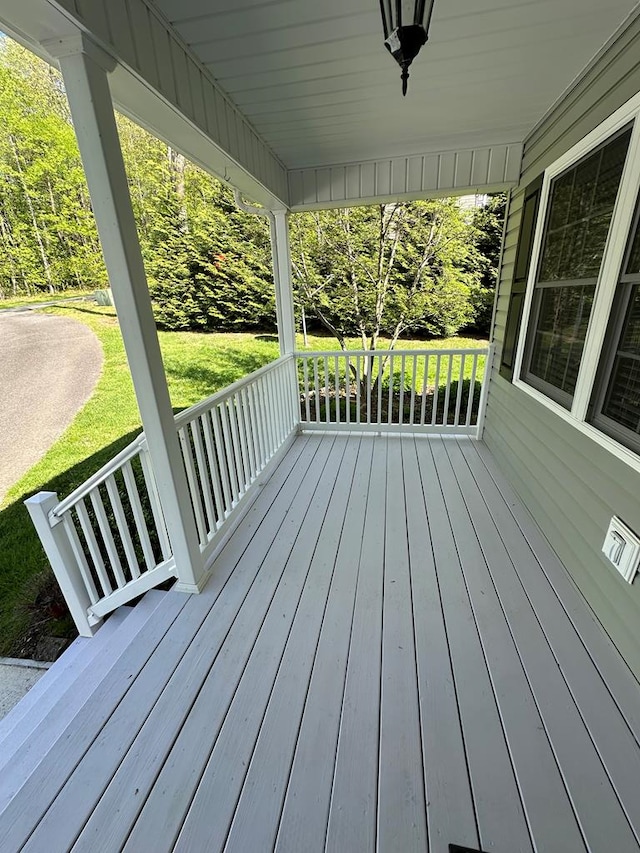 wooden terrace featuring a porch and a yard