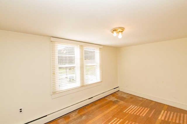 empty room featuring hardwood / wood-style floors and a baseboard radiator