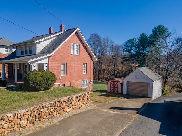 view of home's exterior featuring a storage unit, covered porch, a lawn, and a garage