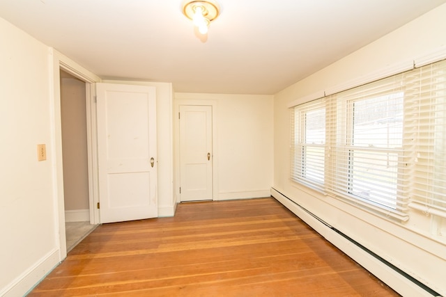 spare room with wood-type flooring and a baseboard heating unit