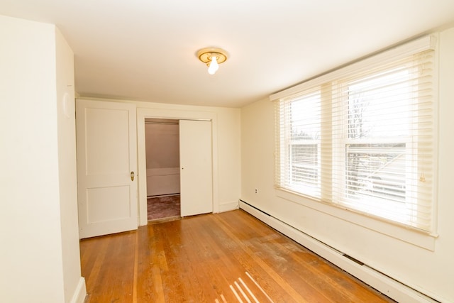 empty room with hardwood / wood-style floors and a baseboard radiator