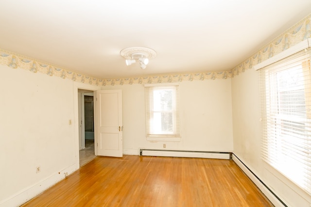 empty room featuring hardwood / wood-style flooring and a baseboard radiator