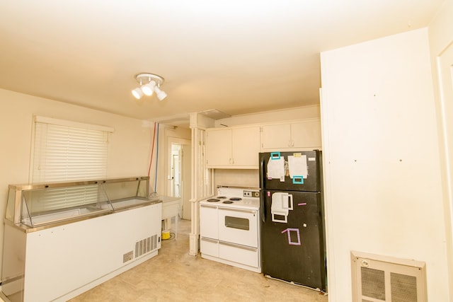 kitchen featuring black refrigerator, white cabinetry, and white electric stove