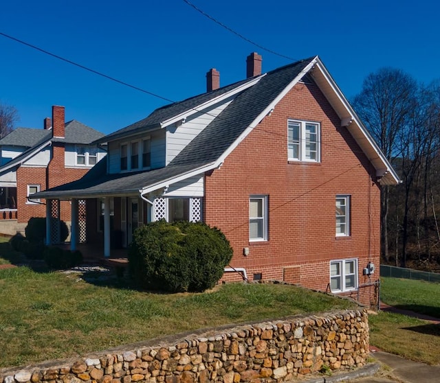view of side of home with covered porch and a lawn
