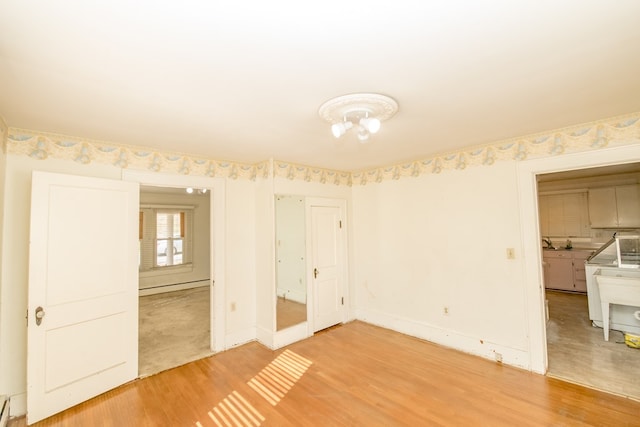 unfurnished bedroom featuring a baseboard heating unit and hardwood / wood-style floors