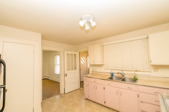 kitchen with sink, white cabinets, and baseboard heating