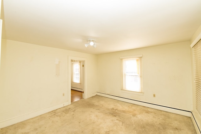 carpeted empty room featuring a baseboard heating unit