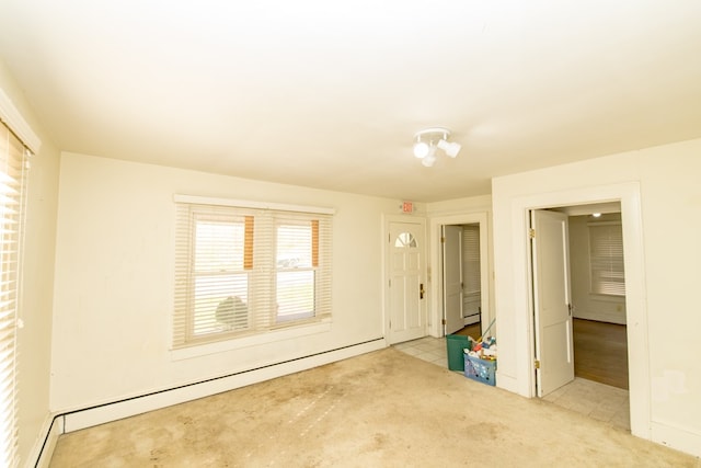 unfurnished room with light colored carpet and a baseboard heating unit