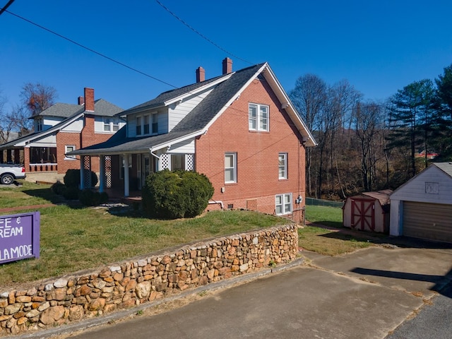 view of home's exterior featuring a garage, a porch, an outbuilding, and a lawn