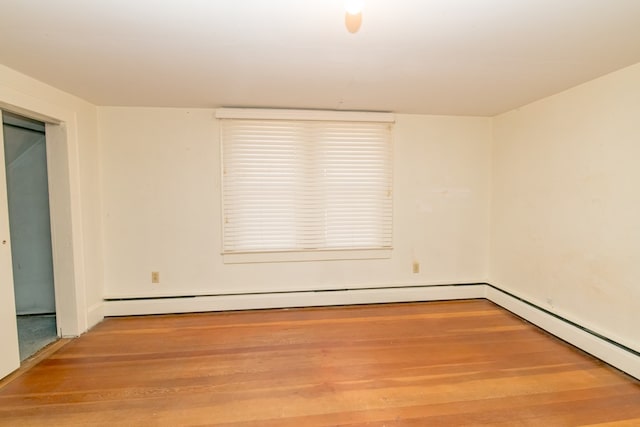 spare room featuring wood-type flooring and a baseboard radiator