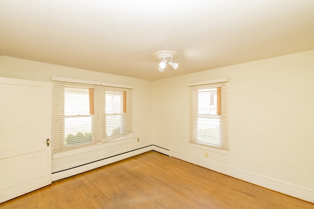 spare room featuring wood-type flooring, a wealth of natural light, and a baseboard heating unit