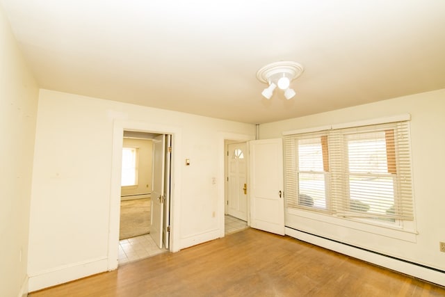 empty room with hardwood / wood-style flooring and a baseboard radiator