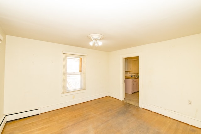 unfurnished room with light hardwood / wood-style floors and a baseboard heating unit
