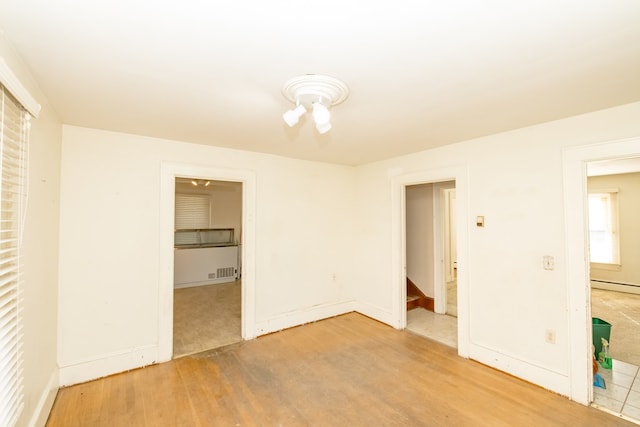 unfurnished bedroom with wood-type flooring and a baseboard radiator