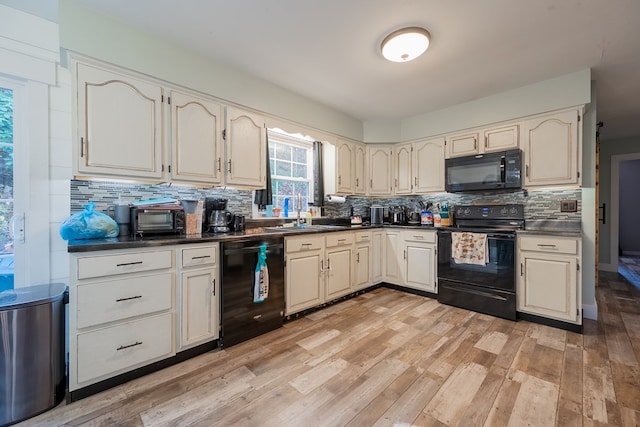 kitchen featuring tasteful backsplash, sink, light hardwood / wood-style floors, and black appliances