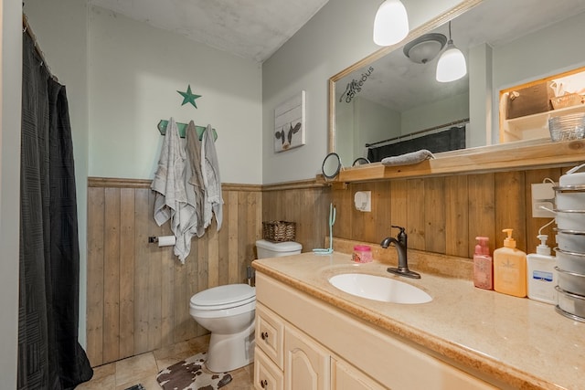 bathroom featuring vanity, toilet, and wood walls