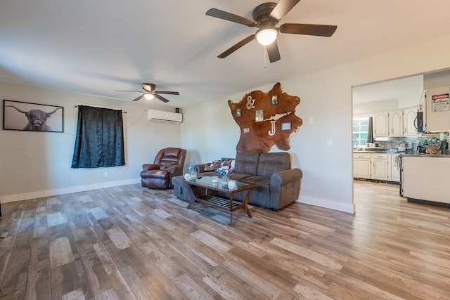 living room with a wall unit AC, light hardwood / wood-style floors, and ceiling fan