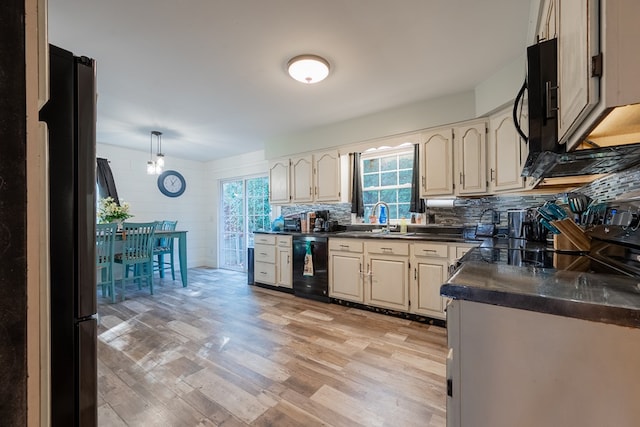 kitchen featuring tasteful backsplash, sink, light wood-type flooring, and black appliances