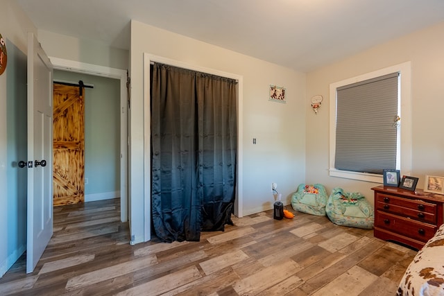 unfurnished bedroom featuring hardwood / wood-style flooring, a barn door, and a closet