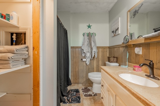 bathroom with vanity, wooden walls, and toilet