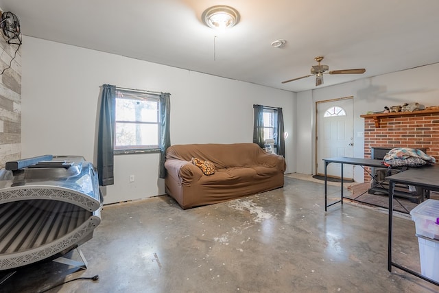 living room featuring a brick fireplace, concrete floors, and ceiling fan