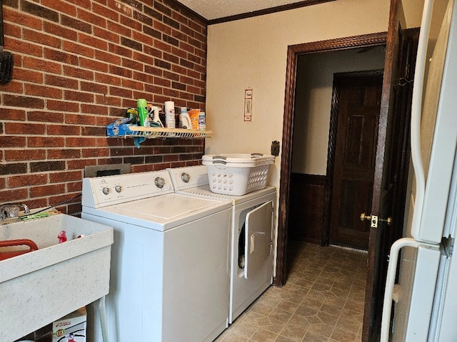 419 Tanglewood Dr, Glade Spring, VA 24340 - washroom with a sink, laundry area, brick wall, crown molding, and washing machine and dryer