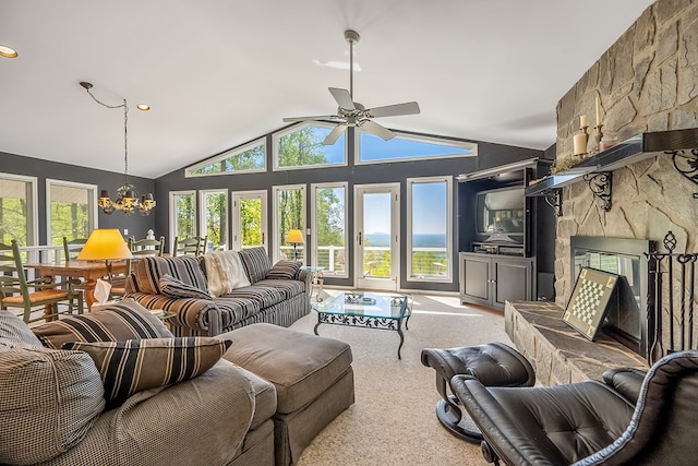 carpeted living room featuring vaulted ceiling, a fireplace, and ceiling fan with notable chandelier